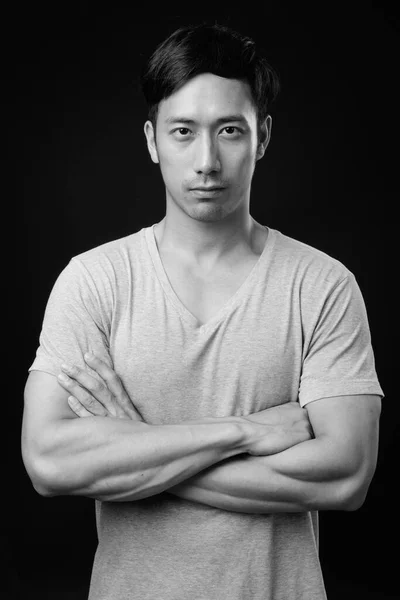 Giovane bello asiatico uomo contro nero sfondo — Foto Stock