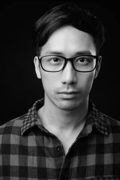 Giovane bello asiatico uomo contro nero sfondo — Foto Stock