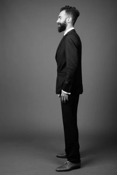 Joven guapo barbudo empresario persa contra fondo gris —  Fotos de Stock