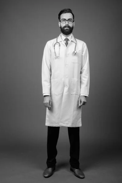 Joven guapo barbudo médico hombre persa contra fondo gris — Foto de Stock