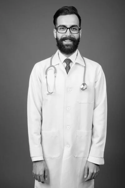 Fiatal jóképű szakállas perzsa férfi orvos ellen szürke háttér — Stock Fotó