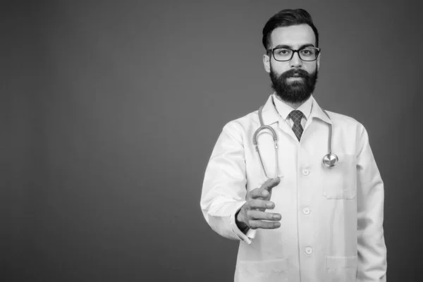 Joven guapo barbudo médico hombre persa contra fondo gris — Foto de Stock