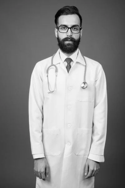 Νεαρός όμορφος γενειοφόρος Πέρσης άνδρας γιατρός σε γκρι φόντο — Φωτογραφία Αρχείου