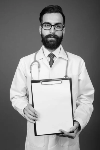 Joven guapo barbudo médico hombre persa contra fondo gris — Foto de Stock