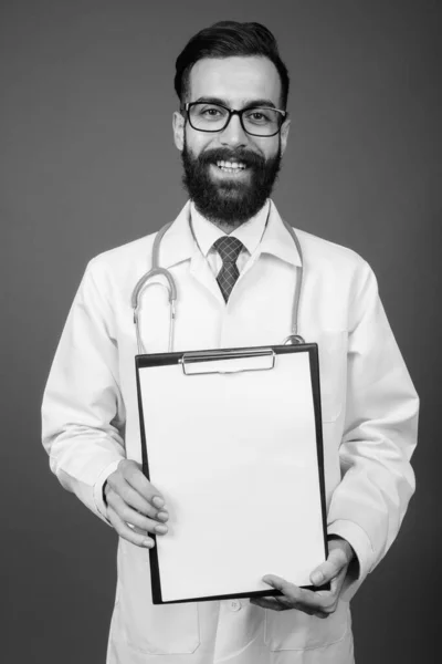 Joven guapo barbudo médico hombre persa contra fondo gris — Foto de Stock