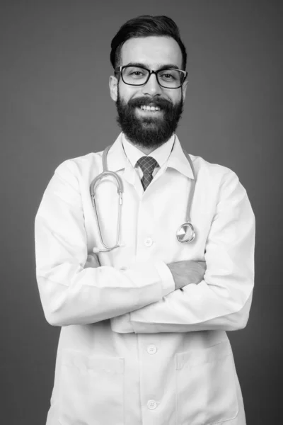Young handsome bearded Persian man doctor against gray background — Stock Photo, Image