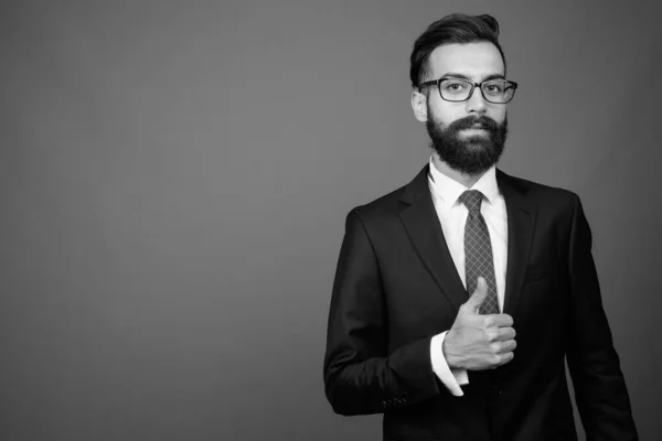Joven guapo barbudo empresario persa contra fondo gris —  Fotos de Stock