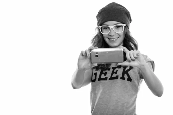 Estudio de disparo de chica geek feliz sonriendo mientras toma una foto con el teléfono móvil — Foto de Stock