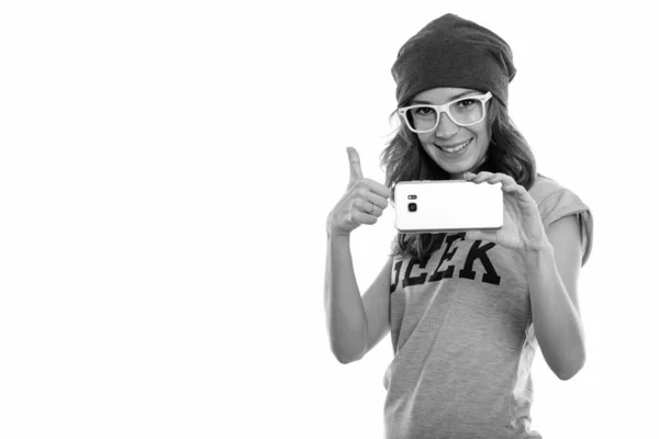 スタジオショットの幸せなオタクの女の子笑顔とともに写真を撮りながら携帯電話と親指を放棄 — ストック写真