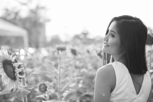 Gülümseyen ve çiçek açan ayçiçeği tarlası düşünme genç mutlu Asyalı kadın profil görünümü — Stok fotoğraf