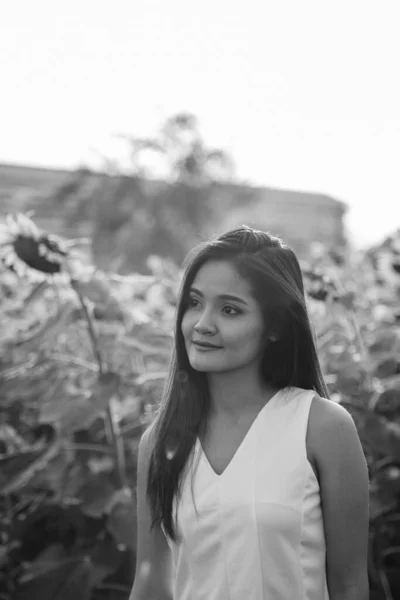 Mladá krásná Asijské žena myslí při pohledu na dálku v poli rozkvetlých slunečnic — Stock fotografie