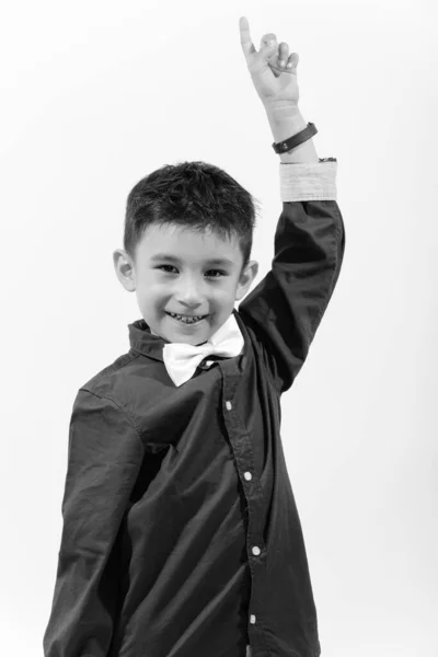 Estúdio tiro de menino feliz bonito sorrindo e apontando o dedo para cima — Fotografia de Stock