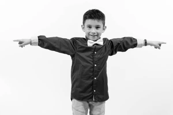 Estúdio tiro de menino feliz bonito sorrindo e apontando os dedos em direções diferentes — Fotografia de Stock