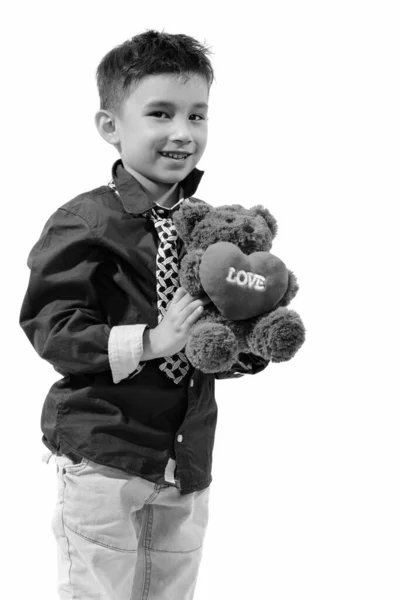 工作室拍摄的可爱快乐男孩微笑着拿着泰迪熊的心和爱的标志 — 图库照片