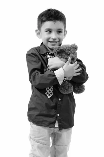 Estúdio tiro de menino feliz bonito sorrindo e abraçando ursinho de pelúcia com coração e sinal de amor — Fotografia de Stock