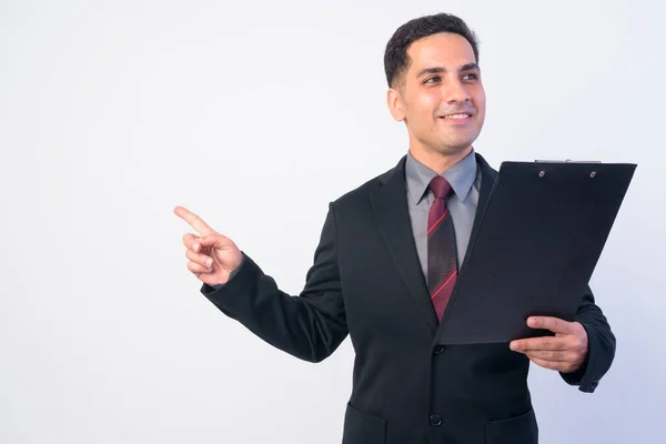 Retrato de feliz hombre de negocios persa en traje apuntando con el dedo mientras sostiene el portapapeles —  Fotos de Stock