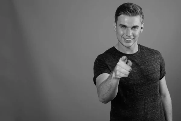 Portrait of young handsome man against gray background in black and white — Stock Photo, Image