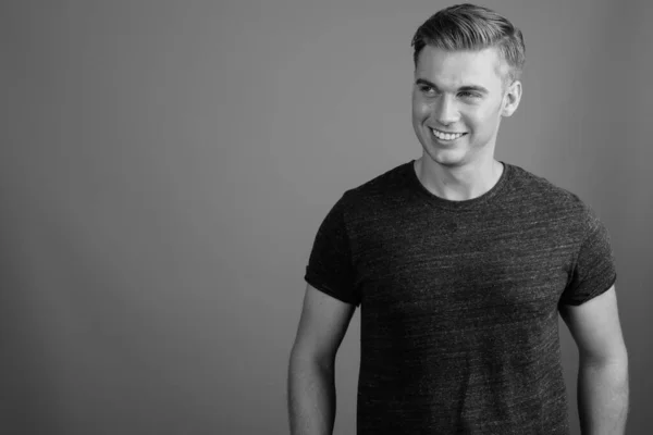 Retrato de homem bonito jovem contra fundo cinza em preto e branco — Fotografia de Stock