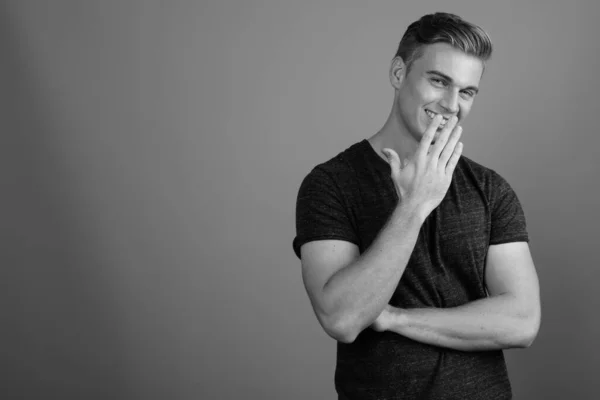 Retrato de homem bonito jovem contra fundo cinza em preto e branco — Fotografia de Stock