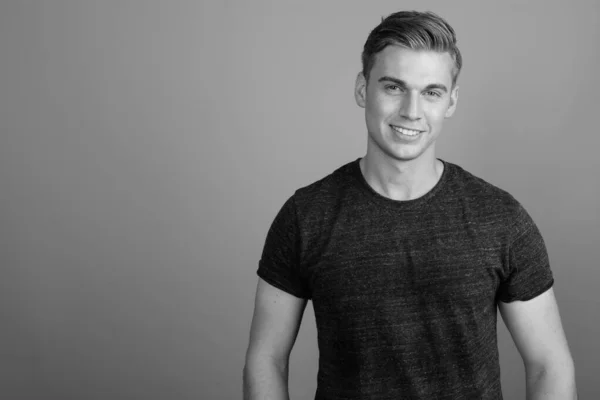 Retrato de homem bonito jovem contra fundo cinza em preto e branco — Fotografia de Stock