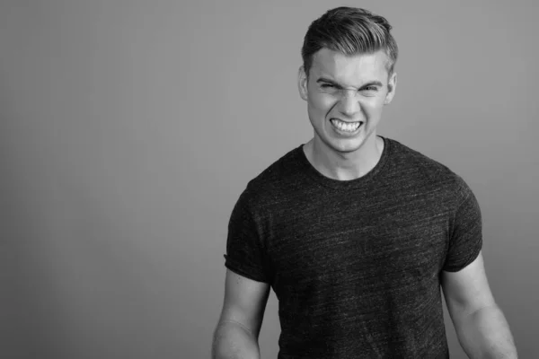 Portrait of young handsome man against gray background in black and white — Stock Photo, Image