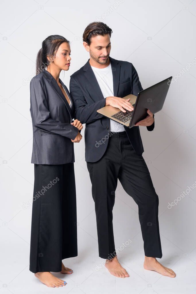 Full body shot of multi ethnic business couple using laptop together