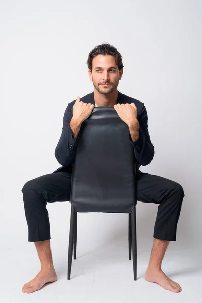 Corpo inteiro tiro de belo empresário hispânico olhando para longe enquanto sentado na cadeira — Fotografia de Stock