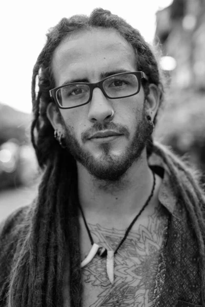 Young handsome Hispanic tourist man with dreadlocks outdoors in black and white — Stock Photo, Image