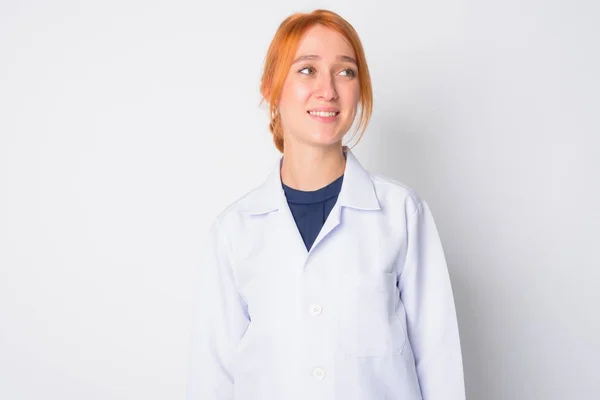 Retrato de feliz jovem bela ruiva mulher médico pensando — Fotografia de Stock