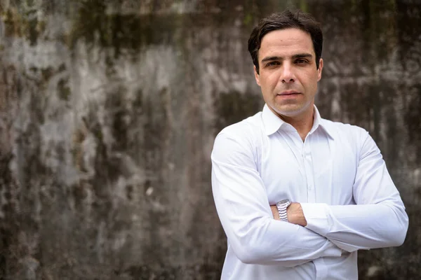 Handsome Persian businessman against concrete wall outdoors — Stock Photo, Image