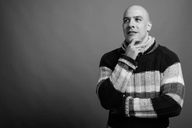 Siyah beyaz arka planda balıkçı yaka kazak giyen yakışıklı, kel adamın stüdyo fotoğrafı.