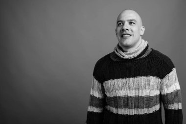 Siyah beyaz arka planda balıkçı yaka kazak giyen yakışıklı, kel adamın stüdyo fotoğrafı.