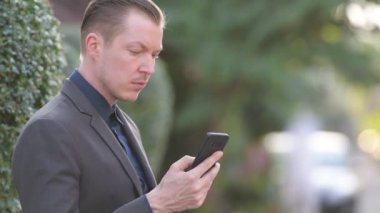 Telefonu açık havada kullanan mutlu genç iş adamının yüzü.