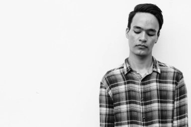 Beyaz duvara karşı siyah beyaz giysili yakışıklı bir Hintli.