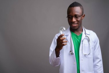 Genç Afrikalı doktorun gri arka planda gözlük taktığı fotoğraf.