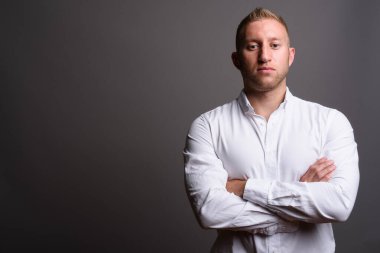 Stüdyo fotoğrafı, sarı saçlı, gri arka planda beyaz gömlek giyen işadamı.