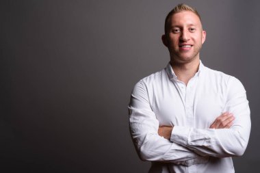 Stüdyo fotoğrafı, sarı saçlı, gri arka planda beyaz gömlek giyen işadamı.