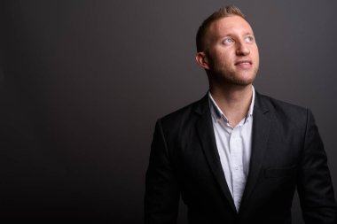 Stüdyo fotoğrafı, sarı saçlı, gri arka planda takım elbiseli bir iş adamı.