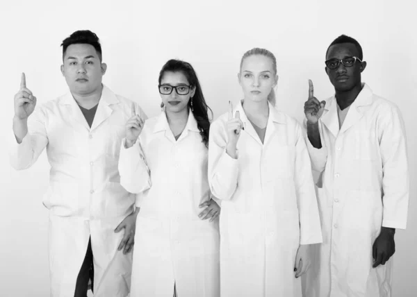 Studio shot of diverse group of multi ethnic doctors pointing finger up together