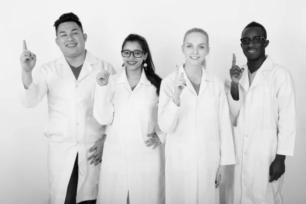 Studio skott av glad mångskiftande grupp av multi etniska läkare leende medan pekar finger tillsammans — Stockfoto