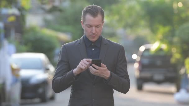 Heureux jeune homme d'affaires beau en utilisant le téléphone en plein air — Video