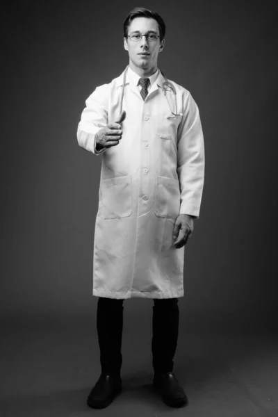 Jovem bonito homem médico contra fundo cinza em preto e branco — Fotografia de Stock