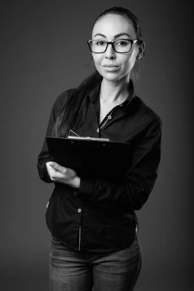 Studio shot of young beautiful businesswoman with eyeglasses in black and white — Stock Photo, Image