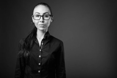 Siyah beyaz gözlüklü genç ve güzel iş kadınının stüdyo fotoğrafı.