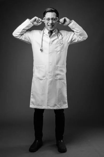 Joven hombre guapo médico con gafas protectoras contra el fondo marrón —  Fotos de Stock