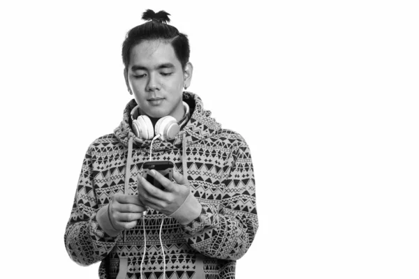 Cep telefonu kullanırken boynuna kulaklık takan yakışıklı Asyalı adamın stüdyo fotoğrafı. — Stok fotoğraf