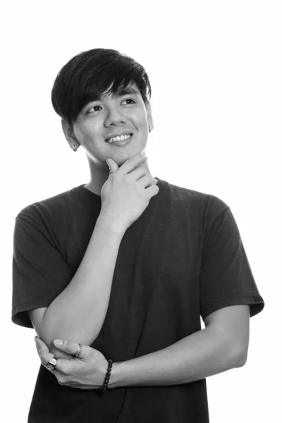 Studio shot van jonge gelukkig Aziatische man die lacht terwijl denken — Stockfoto
