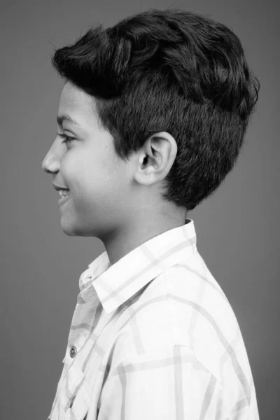 Молодой индийский мальчик в клетчатой рубашке на сером фоне — стоковое фото