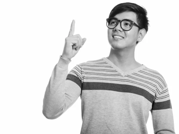 Зйомки молодого щасливого азіатського чоловіка посміхаються і вказують пальцем вгору, думаючи — стокове фото