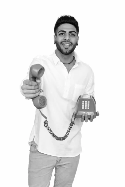 Studioaufnahme eines jungen glücklichen indischen Mannes, der isoliert vor weißem Hintergrund telefoniert — Stockfoto